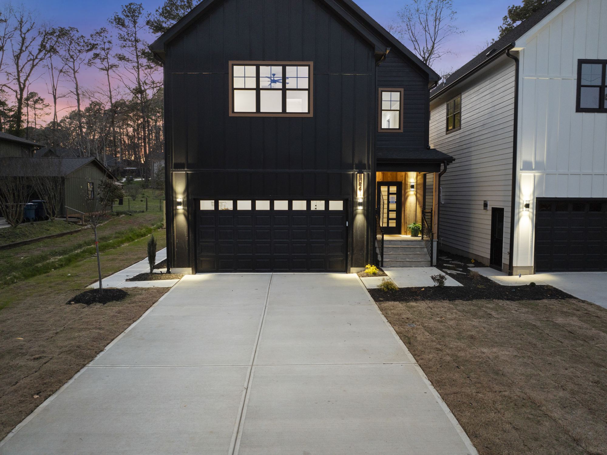5021 Pine Trail Drive at dusk, a black modern farmhouse with lit windows